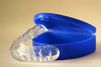 Clear orthodontic retainer in blue protective case, proper retainer storage.