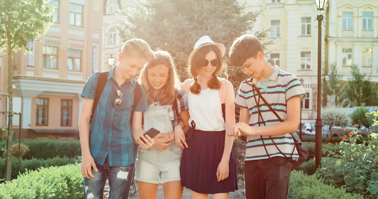 Teens smiling and looking at smartphone, showcasing confident smiles from Dietrich Family Orthodontics.