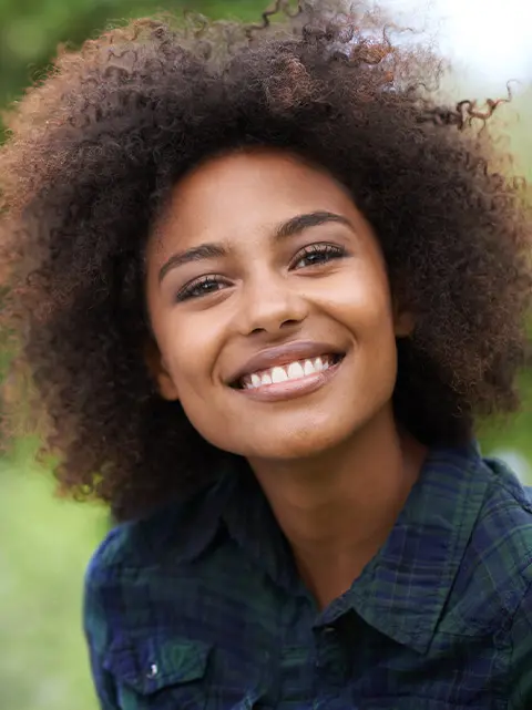 Smiling woman with braces and natural hair, showcasing a confident smile from Dietrich Family Orthodontics in Akron, OH.